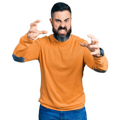 Hispanic man with beard wearing casual winter sweater shouting frustrated with rage, hands trying to strangle, yelling mad