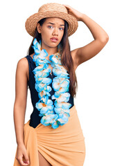 Young beautiful latin girl wearing hawaiian lei and summer hat confuse and wonder about question....