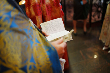 A priest holds a prayer book in his hands at a service in a church.