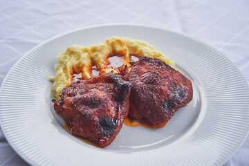 Delicious roasted spicy sweet and hot chicken leg pieces marinated in gochujang korean chilli paste, honey, soya sauce and minced fresh garlic served with mash potatoes on the white porcelain plate.