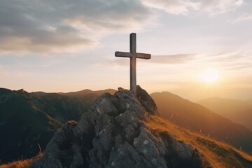 A cross on top of a mountain, illuminated by the warm glow of the sunset. Suitable for religious themes and inspiration - obrazy, fototapety, plakaty