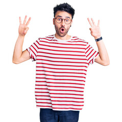 Young hispanic man wearing casual clothes looking surprised and shocked doing ok approval symbol with fingers. crazy expression