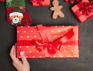 Female hand holding a gift on a table with Christmas decor