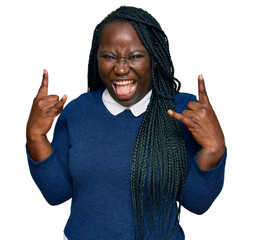 Young black woman with braids wearing casual clothes shouting with crazy expression doing rock...
