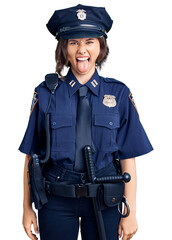 Young beautiful girl wearing police uniform sticking tongue out happy with funny expression. emotion concept.
