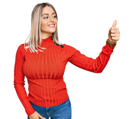 Beautiful blonde woman wearing casual clothes looking proud, smiling doing thumbs up gesture to the...
