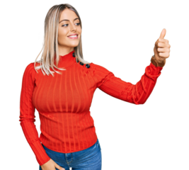 Beautiful blonde woman wearing casual clothes looking proud, smiling doing thumbs up gesture to the side