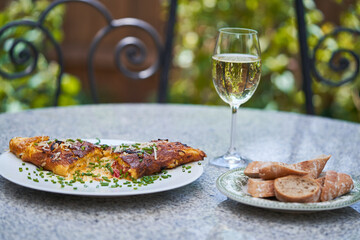French style omelette with cheese and choped chives served as a light and quick lunch outside in the garden restaurant or french bistro with slices of whole grain baguette and glass of white wine.