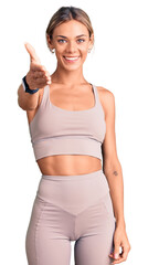 Beautiful caucasian woman wearing sportswear smiling friendly offering handshake as greeting and welcoming. successful business.