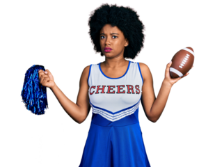 Young african american woman wearing cheerleader uniform holding pompom and football ball clueless and confused expression. doubt concept.