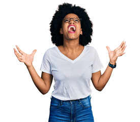 Young african american woman wearing casual white t shirt crazy and mad shouting and yelling with aggressive expression and arms raised. frustration concept.