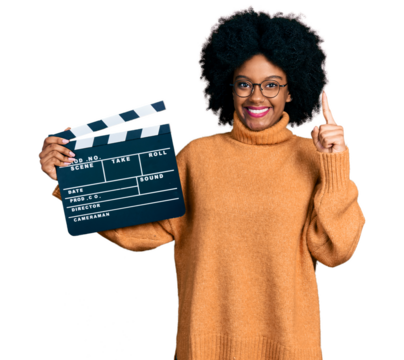 Young african american woman holding video film clapboard smiling with an idea or question pointing finger with happy face, number one