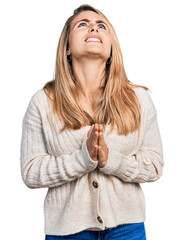 Young blonde woman wearing casual clothes begging and praying with hands together with hope expression on face very emotional and worried. begging.