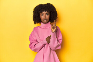 Obraz na płótnie Canvas Teen girl in pink sweatshirt, yellow studio backdrop having some great idea, concept of creativity.