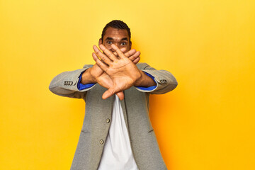 African American man in casual blazer, yellow studio, doing a denial gesture