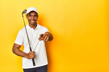 African American golfer in action, posed in a yellow background studio.