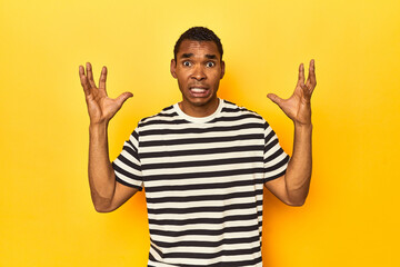 African American man in striped t-shirt, yellow studio, screaming to the sky, looking up, frustrated.