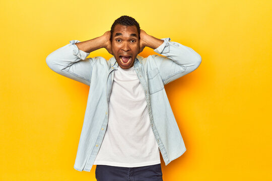 African American man in blue shirt, yellow studio, screaming, very excited, passionate, satisfied with something.