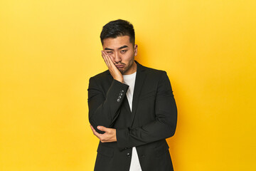 Asian man in black business jacket on yellow studio who is bored, fatigued and need a relax day.