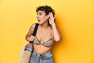 Caucasian woman in bikini with beach bag, studio trying to listening a gossip.