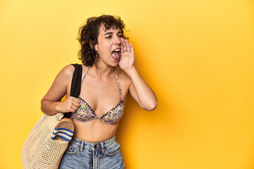 Caucasian woman in bikini with beach bag, studio shouting and holding palm near opened mouth.