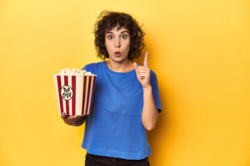 Curly-haired woman with popcorn for movie, studio having some great idea, concept of creativity.
