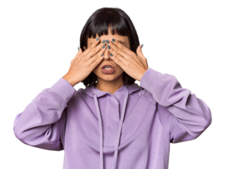 Young Hispanic woman with short black hair in studio afraid covering eyes with hands.