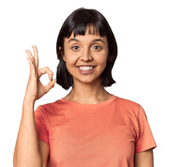 Young Hispanic woman with short black hair in studio cheerful and confident showing ok gesture.