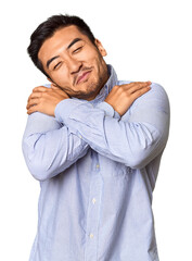 Young Chinese man in studio background hugs, smiling carefree and happy.
