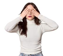 Young Caucasian woman in a studio setting afraid covering eyes with hands.
