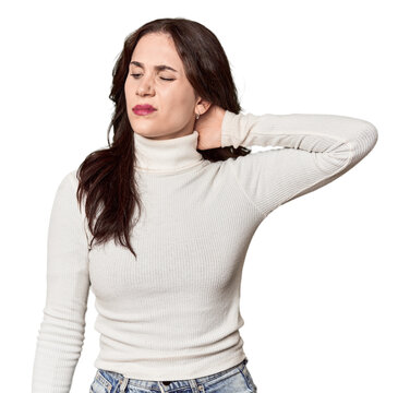 Young Caucasian woman in a studio setting having a neck pain due to stress, massaging and touching it with hand.