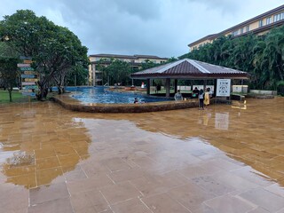 Overcast Sky Over a Luxurious Tropical Resort Featuring a Large Pool, Central Gazebo, and Lush Palm Trees on a Rainy Day