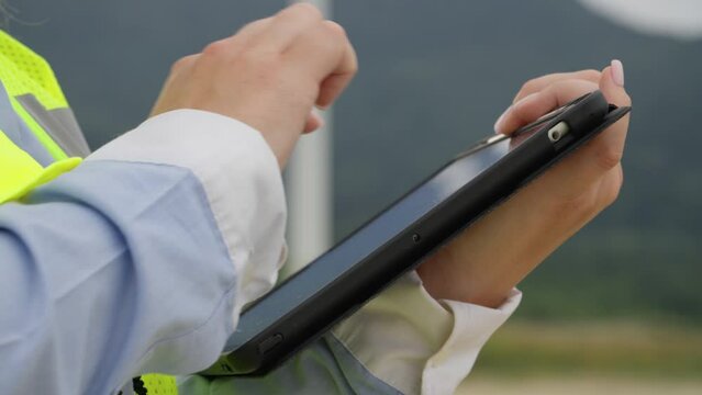 Technological tools for green purposes: an engineer with a tablet improves windmills. Setting up mobile communications and satellite Internet. Record information on a digital tablet