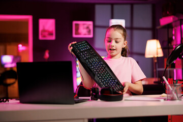 Happy child reviewing mechanical keyboard received from sponsoring brand to promote it. Young media...