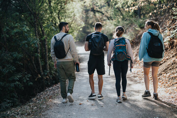 Athletic friends enjoy a sunny day hiking in the autumn wilderness. They camp, exercise, and have fun conversations amidst the green landscape. Healthy and happy, they explore nature together.