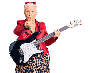 Senior beautiful woman with blue eyes and grey hair wearing a modern look playing electric guitar pointing with finger up and angry expression, showing no gesture