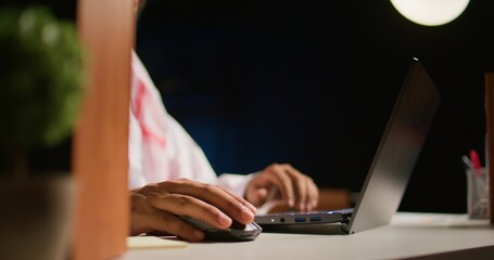 Close up shot of hardworking businessman using laptop keyboard and mouse at office desk to surf the internet. Company executive typing on digital device, finishing tedious paperwork