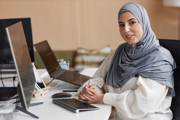 Portrait of Muslim young woman as female software developer smiling and looking at camera at...