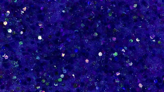 Multicolored blue particles or spangles float in a viscous liquid. Glitter texture. Particles blue background. Shining sparkles. 