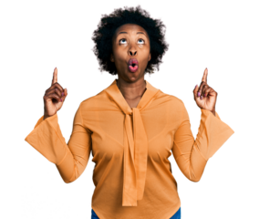 African american woman with afro hair wearing elegant shirt amazed and surprised looking up and pointing with fingers and raised arms.