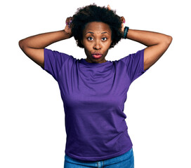 African american woman with afro hair wearing casual purple t shirt doing funny gesture with finger over head as bull horns