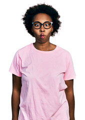 African american woman with afro hair wearing casual clothes and glasses making fish face with lips, crazy and comical gesture. funny expression.