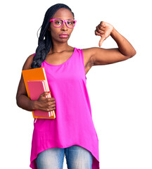Young african american woman wearing glasses holding book with angry face, negative sign showing...