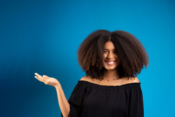 Young woman with black power hair smiling and with her palm up.