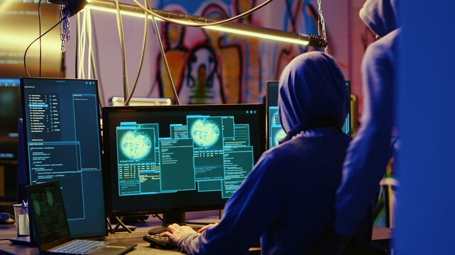 Hackers happy after successfully doing computer sabotage using encryption trojan ransomware in hidden base. Cybercriminals demanding ransom money from victims after gaining access to their data