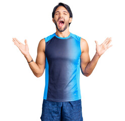 Handsome hispanic man wearing sportswear celebrating mad and crazy for success with arms raised and...