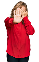 Middle age blonde woman wearing casual shirt over red background covering eyes with hands and doing stop gesture with sad and fear expression. embarrassed and negative concept.