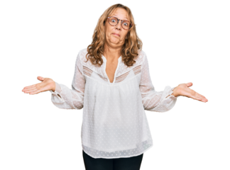 Middle age blonde woman wearing casual white shirt and glasses clueless and confused expression with arms and hands raised. doubt concept.