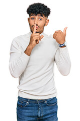Young arab man wearing casual winter sweater asking to be quiet with finger on lips pointing with...
