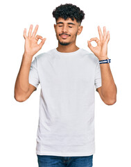 Young arab man wearing casual white t shirt relaxed and smiling with eyes closed doing meditation gesture with fingers. yoga concept.